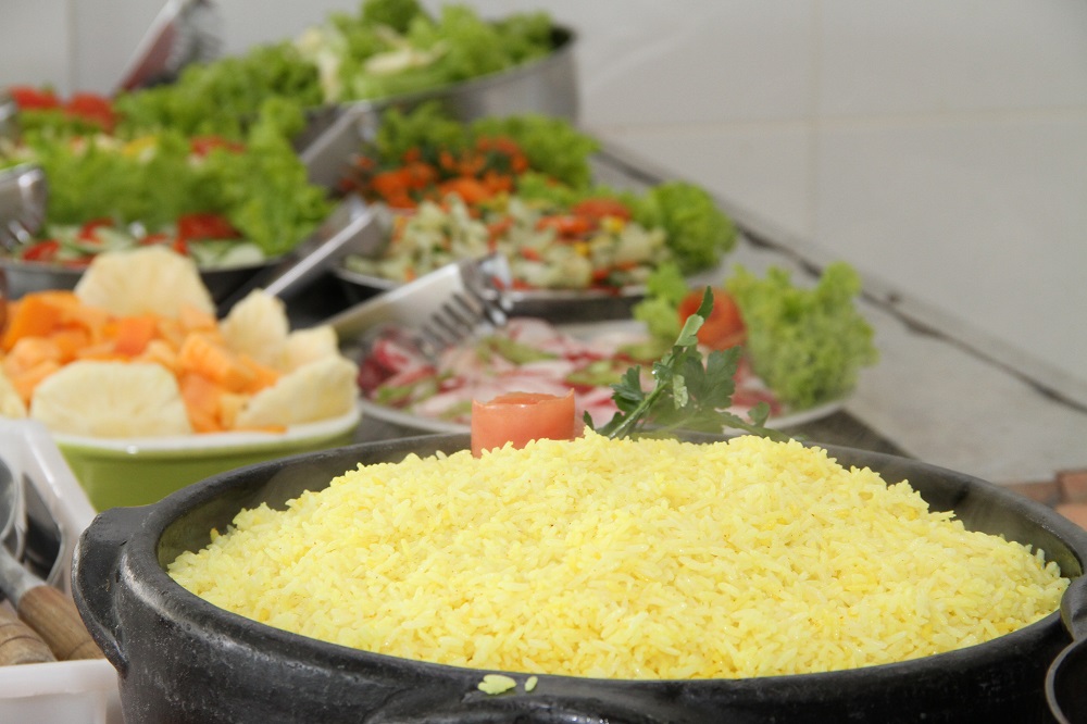 Mesa posta com panela de arroz e diversos pratos de saladas  