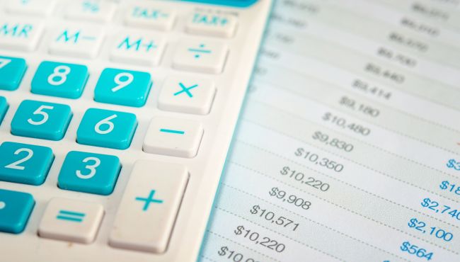 Imagem de uma calculadora em cima de um papel com números representando os custos da atividade leiteira.