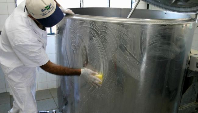 Homem realizando a limpeza do tanque de refrigeração.